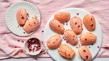 Two plates with raspberry flavoured madeleines scattered with dried rose petals