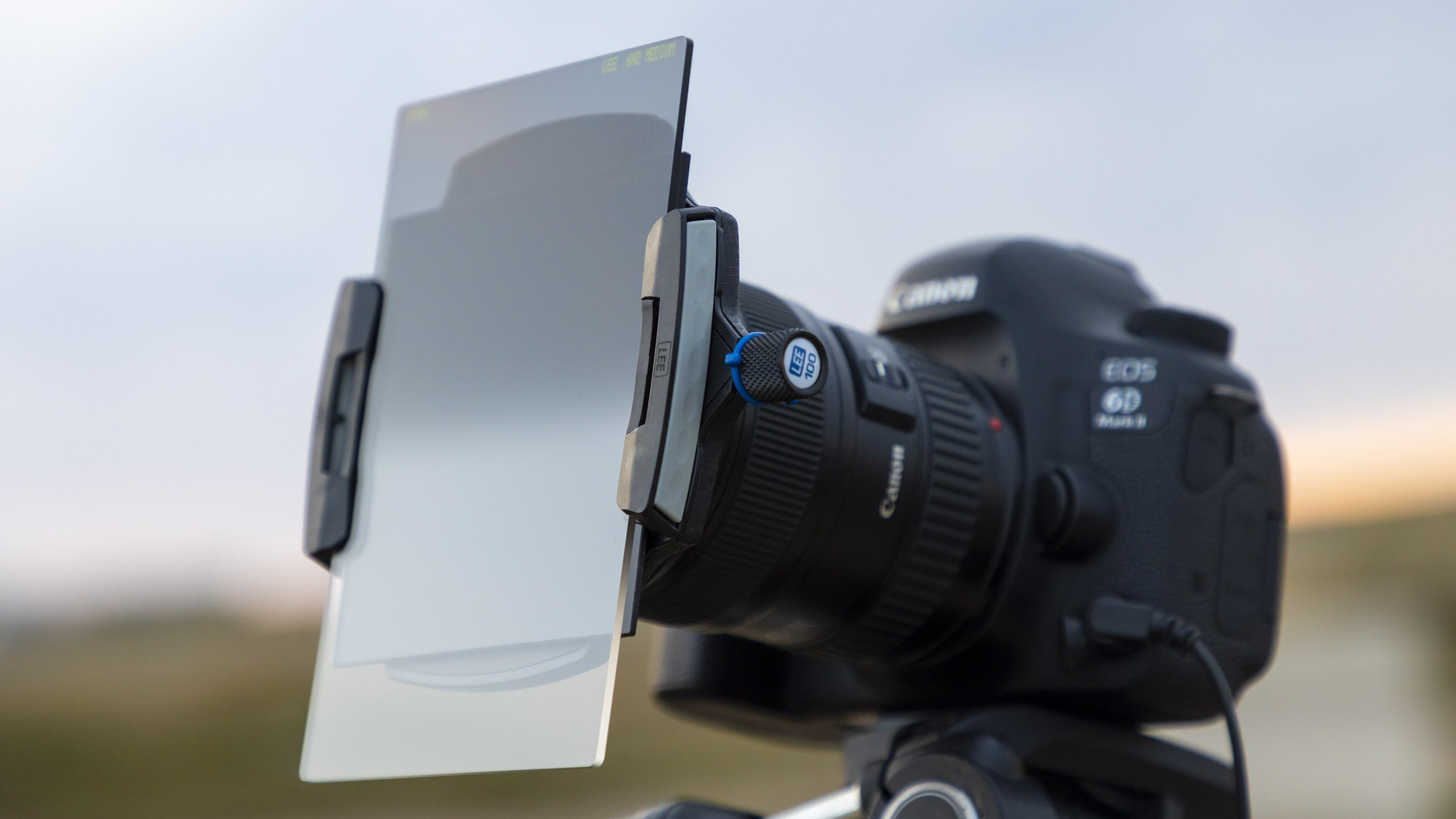 A photographer using a camera with a square filter holder attached and a large ND grad on the front of it