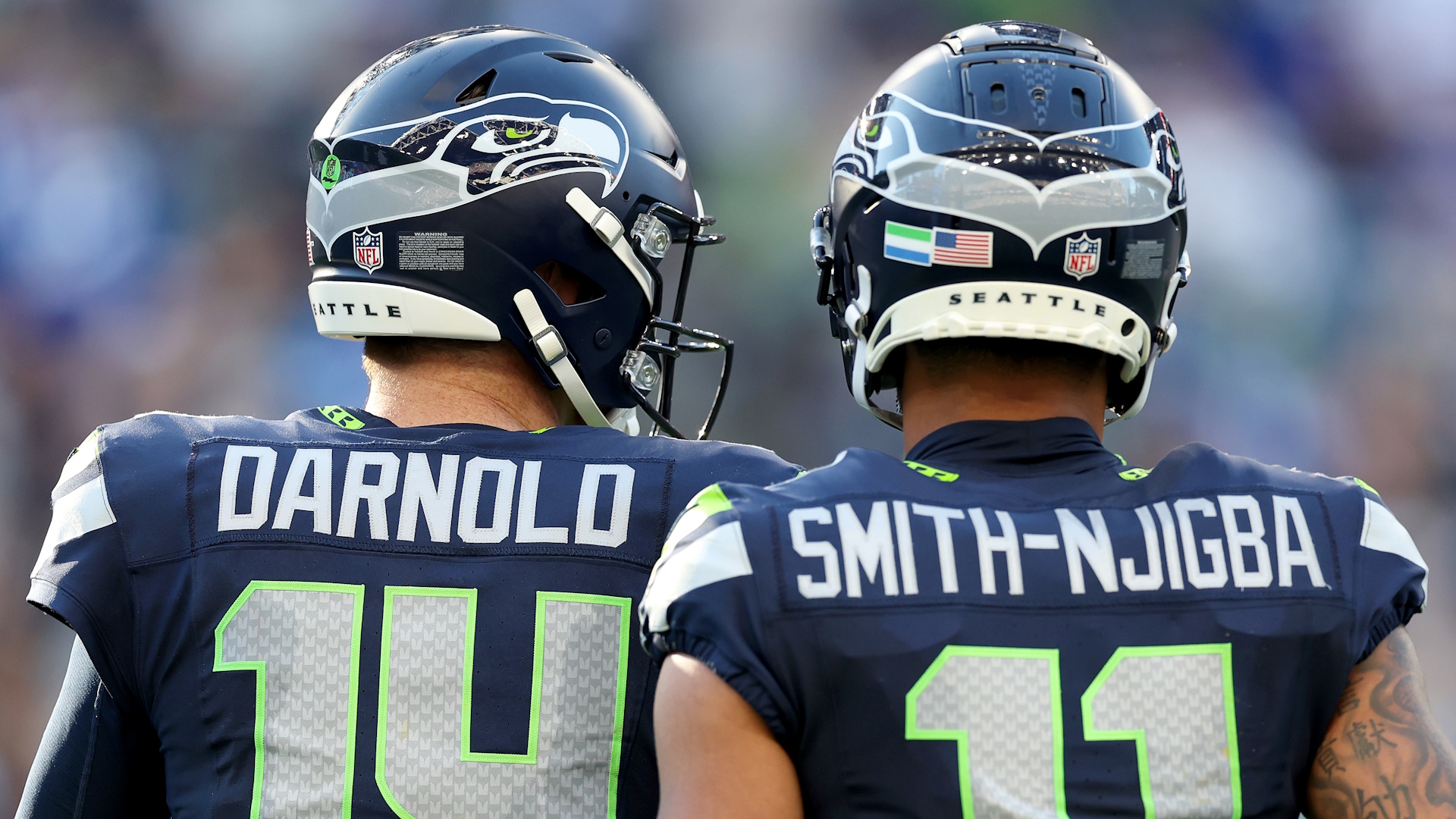 Sam Darnold #14 and Jaxon Smith-Njigba #11 of the Seattle Seahawks standing side-by-side during an NFL game.
