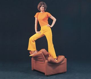 An image of a woman standing on a sofa