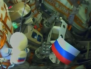 "Fyodor," a Russian robot officially designated Skybot F-850, sits in the commander's seat of the Soyuz MS-14 spacecraft after successfully reaching orbit on Aug. 22, 2019. A Russian flag is clutched in its right hand.