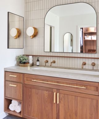 White bathroom with beige tiles and a wood vanity with gold hardware