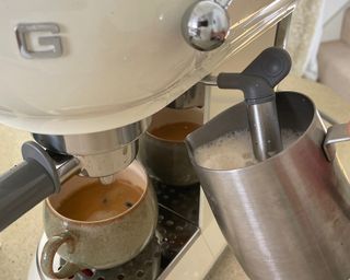 A close-up shot of Helen McCue demonstrating how to use the steam wand on the Smeg coffee maker