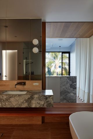 A bathroom with wooden flooring and a large mirror