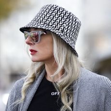 Best lipsticks for older women - Petra van Bremen wearing a black and white bucket hat by Valentino, a black t-shirt by Off-White, black shorts with belt by Off-White, a long silver knitted coat by Balenciaga, transparent frame sunglasses by Westward Leaning, - gettyimages1355367186