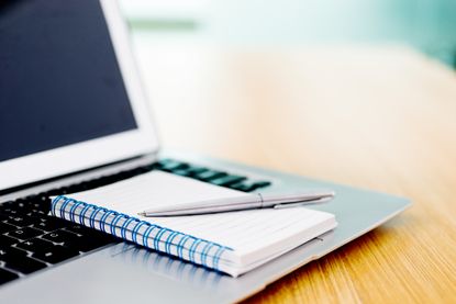 A notebook and pen on top of a laptop