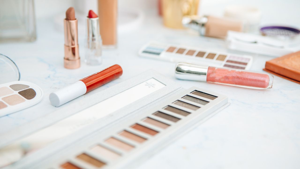 Close up of an array of make-up products scattered across a white dressing table