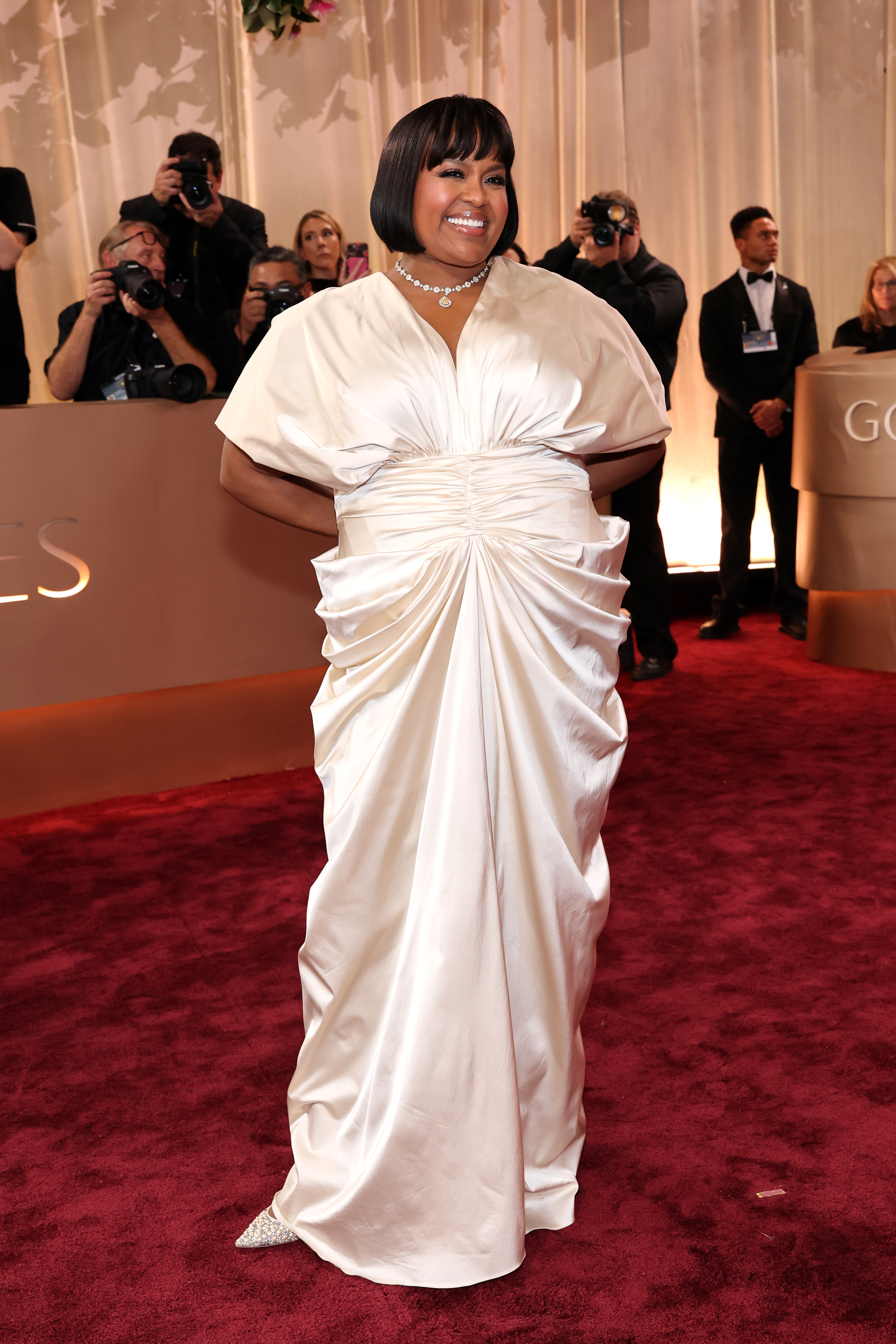 a black woman with short, dark hair wearing a silk cream gown on the red carpet