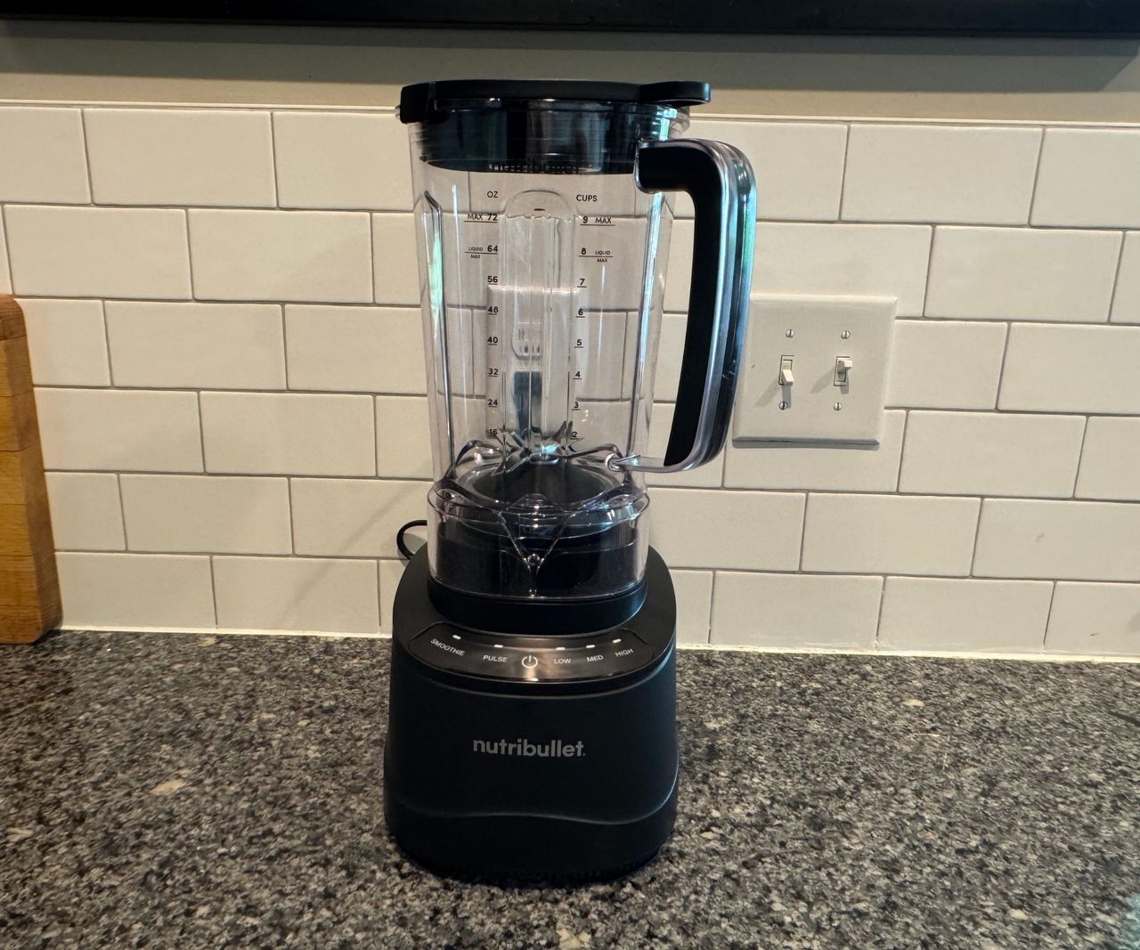A nutribullet PowerCore XL Blender on a stone kitchen counter against white subway tiles.