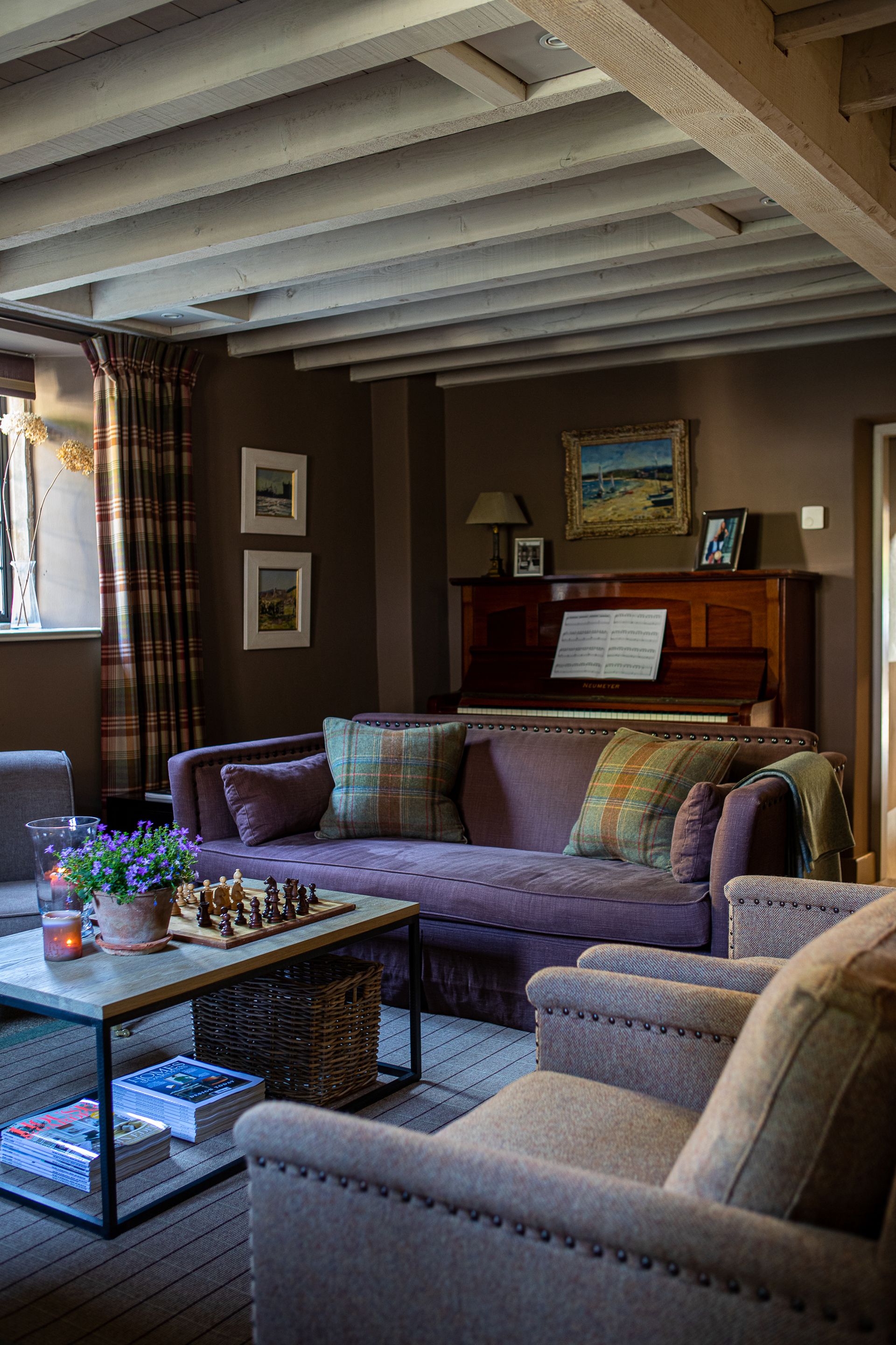 cozy cozy den with purple couch and cream armchairs and beamed ceiling