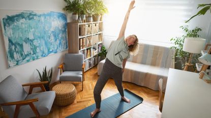 Woman practises yoga in her living room