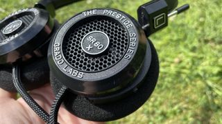 A close-up of the outer cup of the Grado SR80x headphones against a grassy surface.