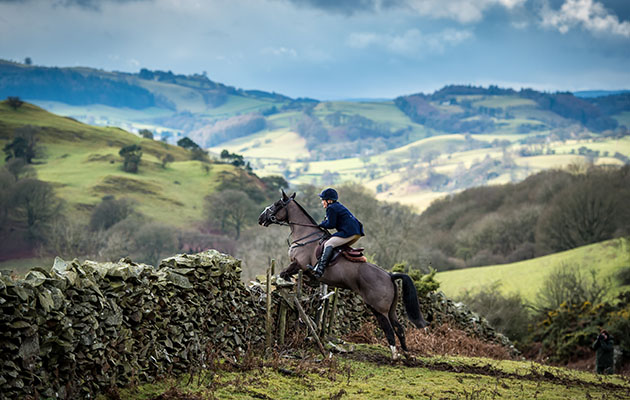 Sue Jones tackles a wall, with the backdrop of emerald grazing