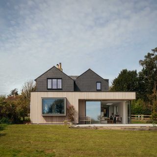 contemporary house with slate hanging tiles and vertical timber cladding with corner sliding doors