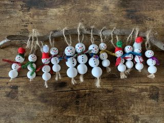 Christmas craft project of hanging snowmen decorations with a wooden backdrop