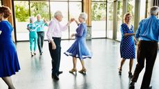 An elderly man twirls his partner on the dance floor.
