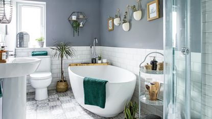 White tiled bathroom with white ladder shelf with plants and circle hanging mirror