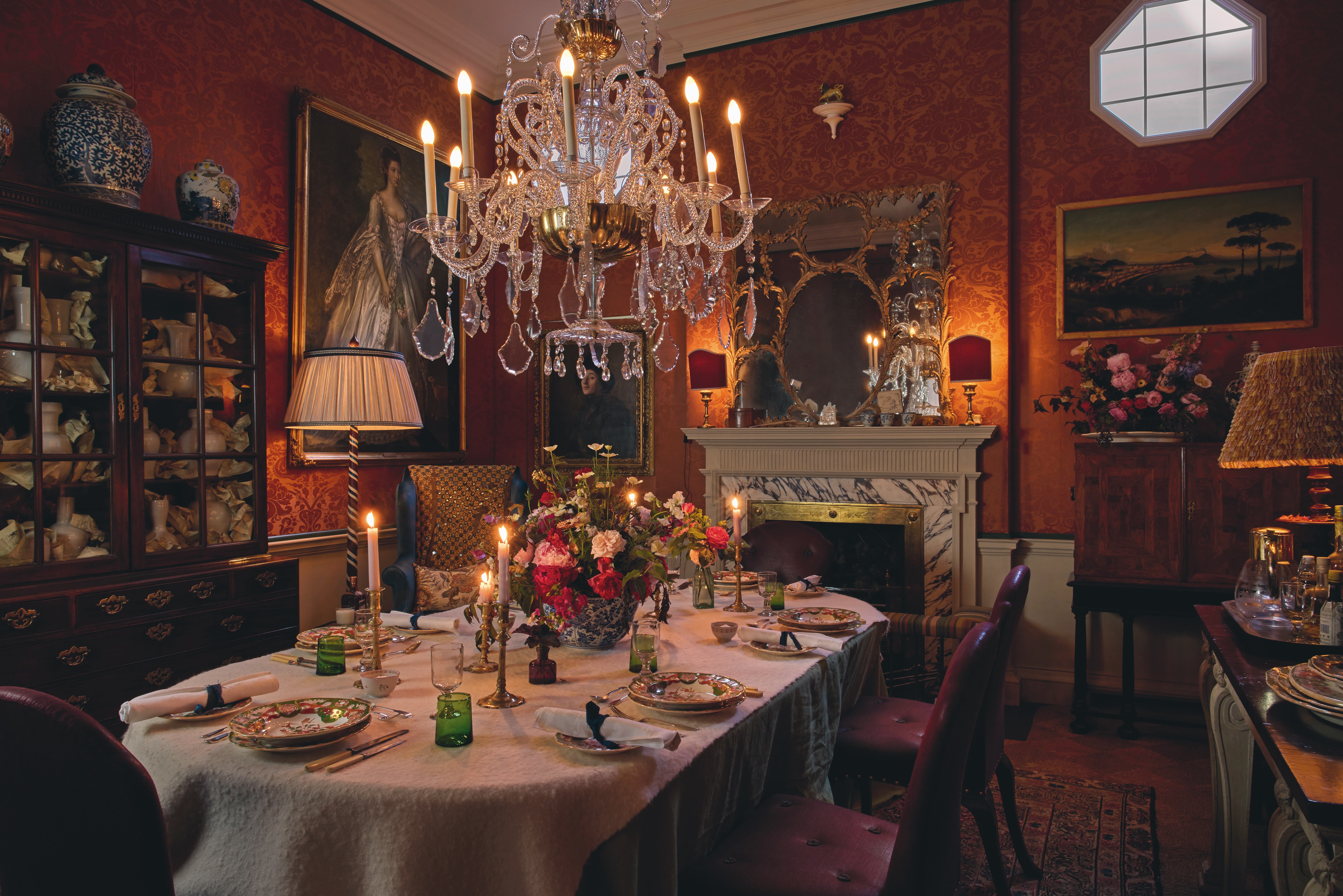 An eclectic dining room with a marble fireplace and a crystal chandelier