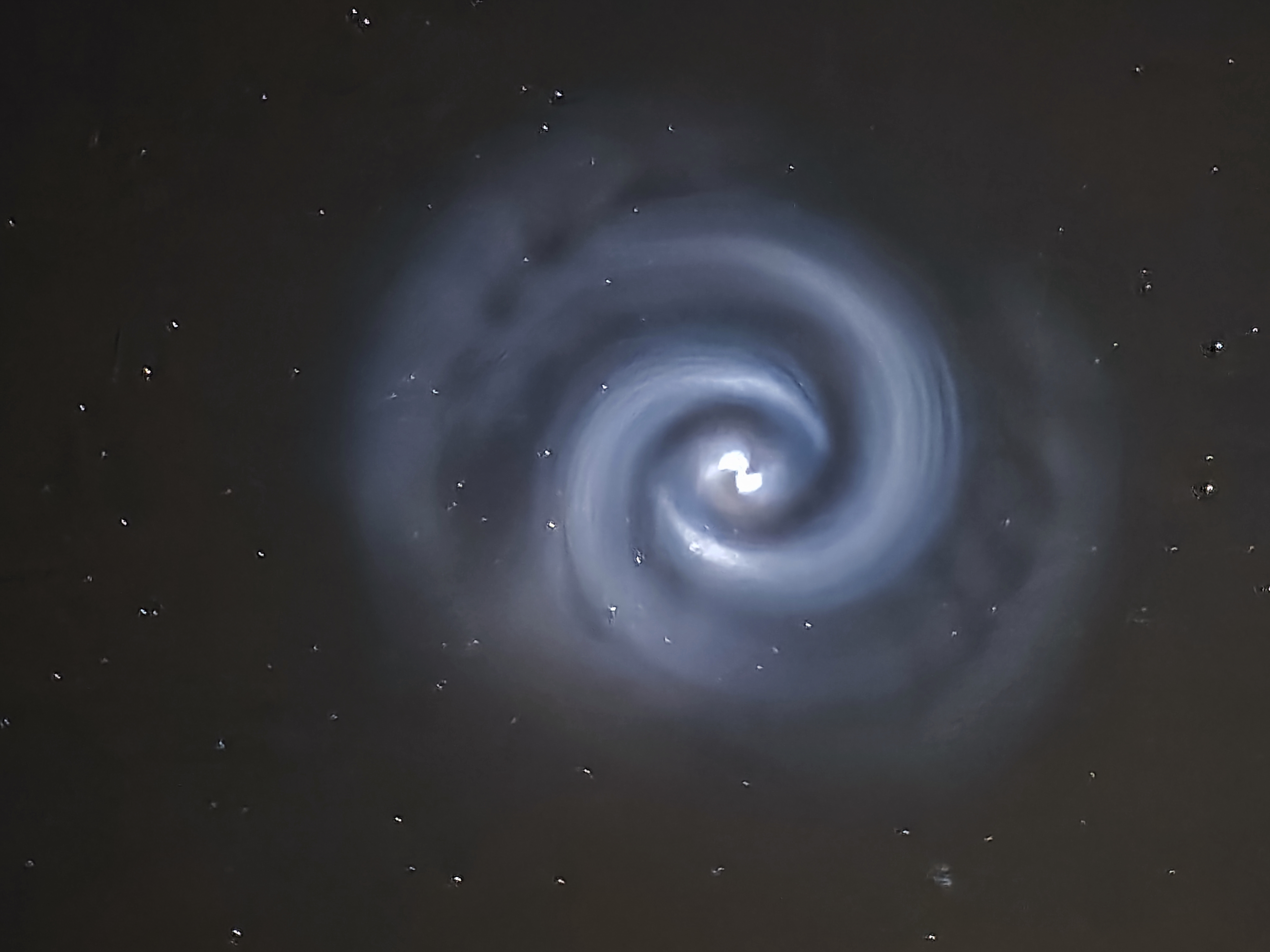 Una espiral azul con un núcleo blanco visto contra un fondo negro estrellado