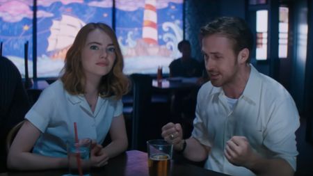 Emma Stone looking forward and Ryan Gosling looking down and passionate while his hands are in fists in La La Land. 