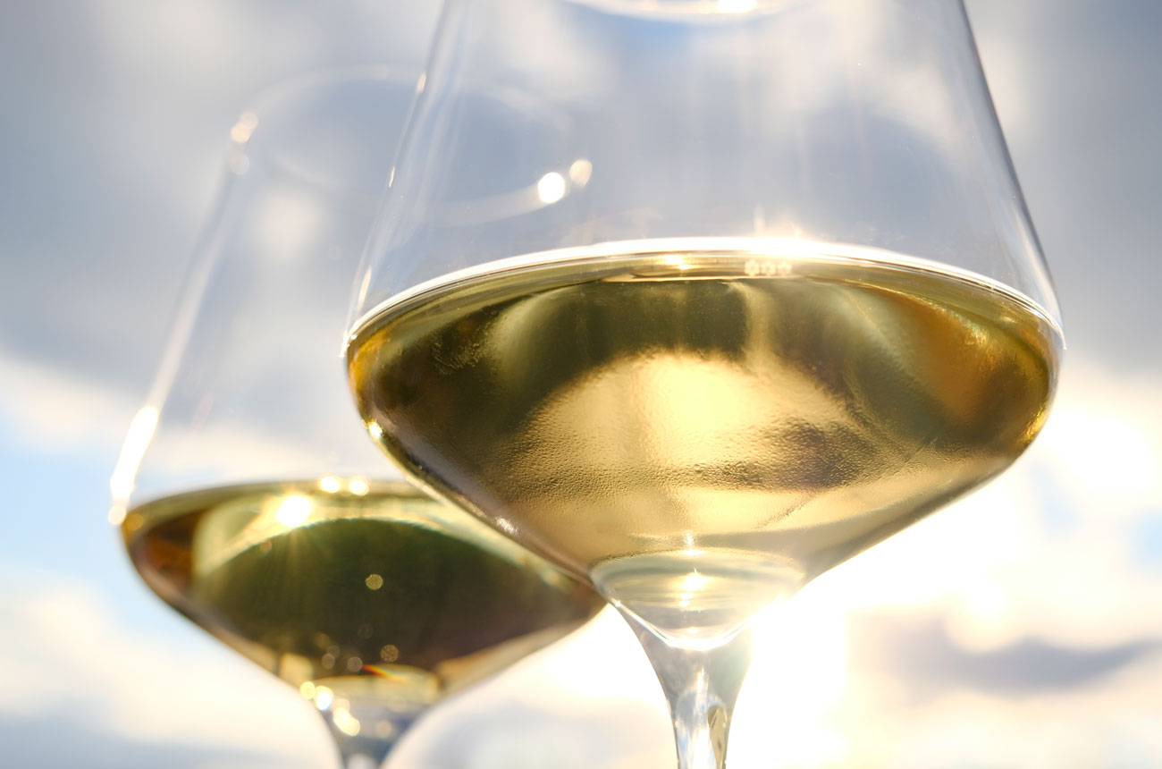 Two glasses of white wine against sunny sky background