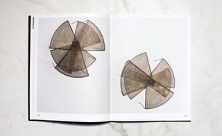 Open page in the book showing a series of low fan structured tables painted in metal with feet in oxidised brass