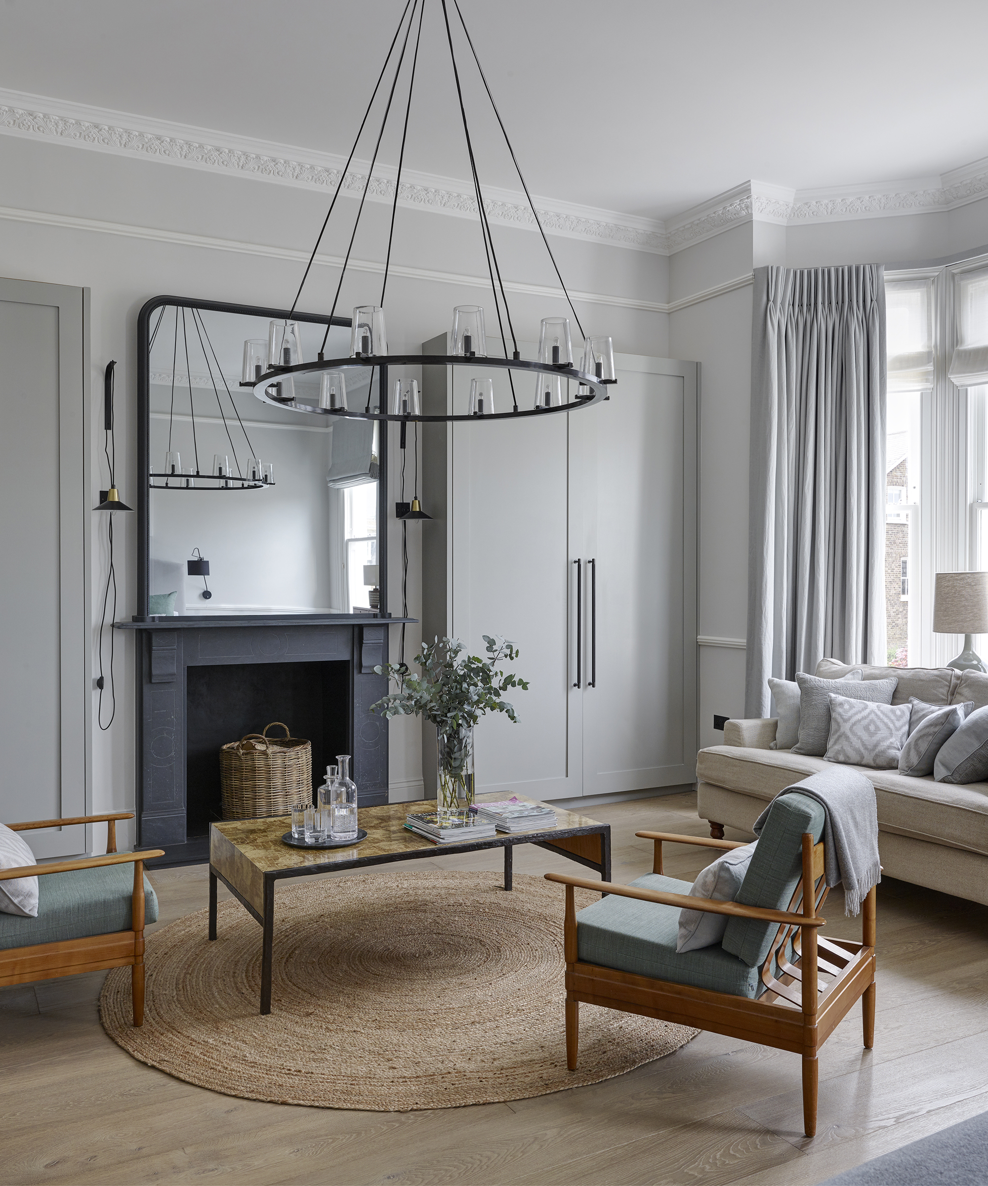 A medieval chandelier in front of a square mirror in a white living room