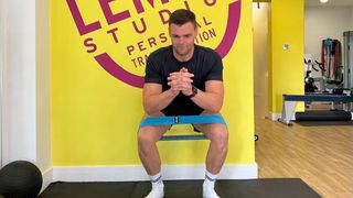 Sam Shaw demonstrates squatting with a resistance band