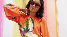 A model wearing an orange, patterned top with billowing sleeves from River Island. 