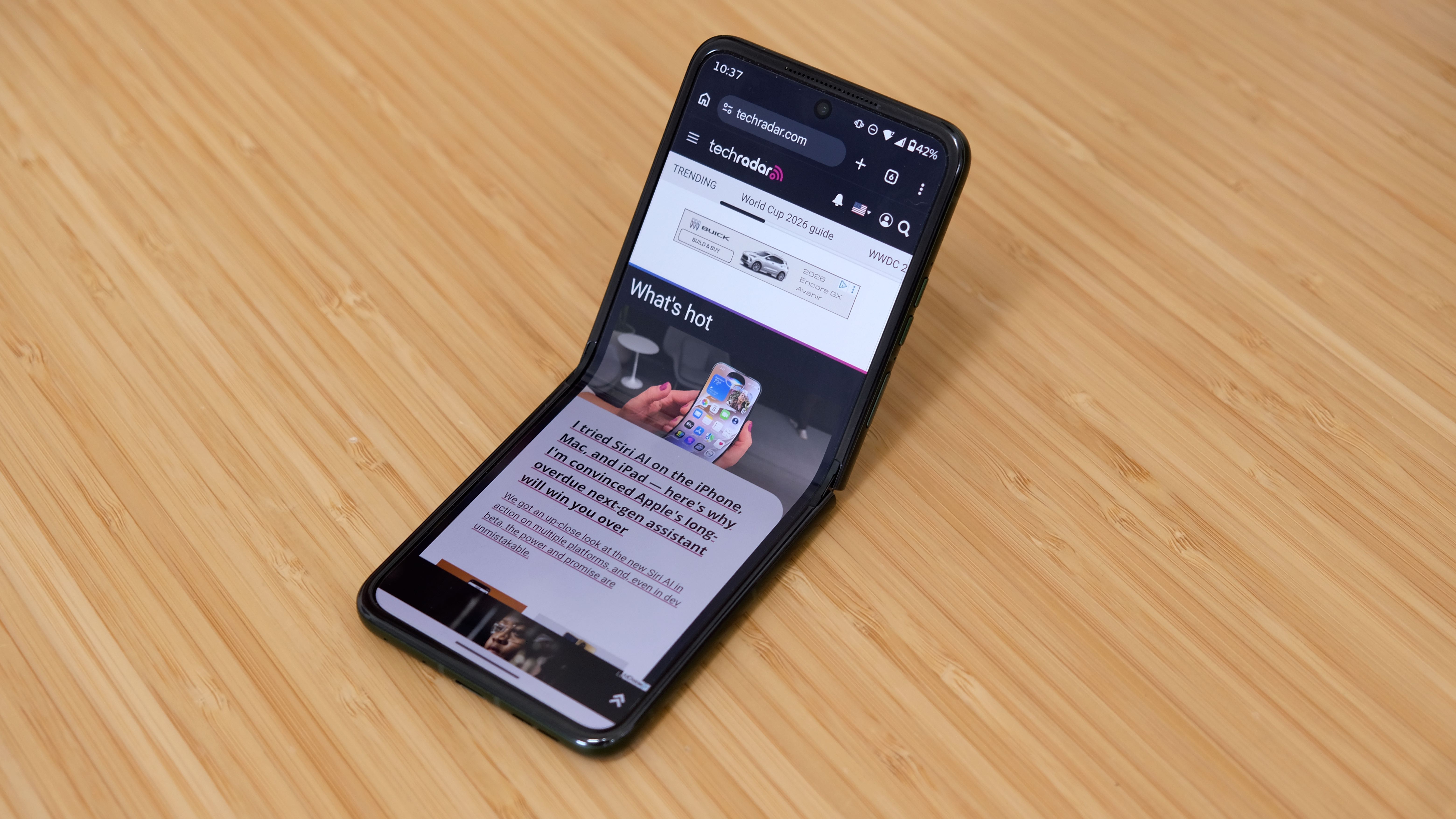 The Motorola Razr Plus 2026 in the hand and on a wooden table