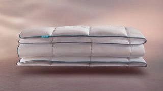 A white duvet folded against a ombre background