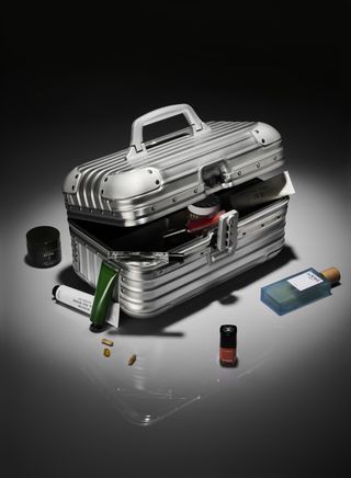 A silver Rimowa vanity case with several beauty products