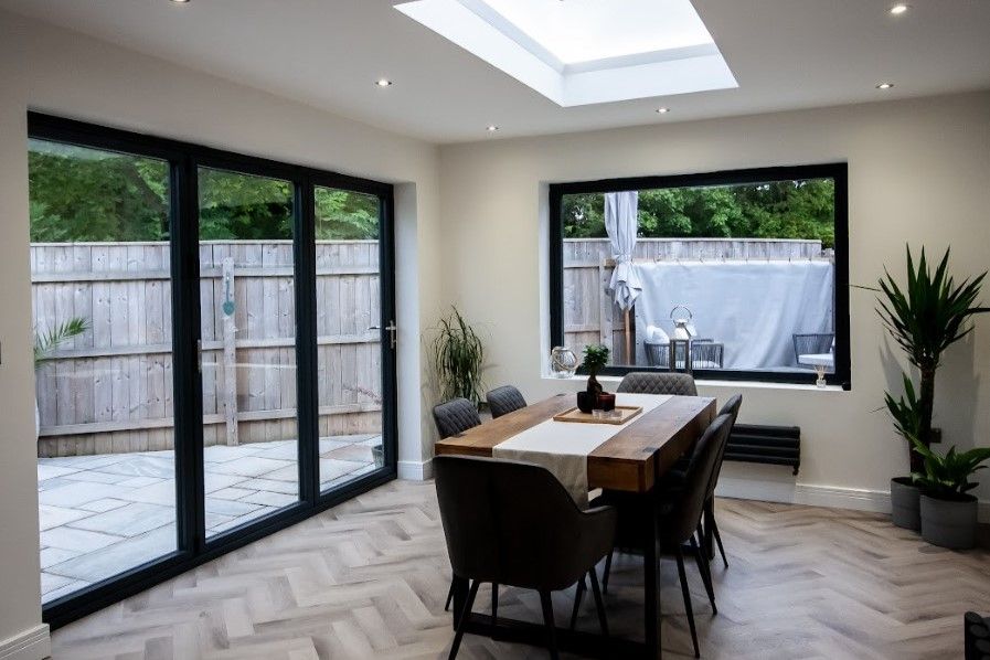 A dining room with roof lantern and black bifold aluminium doors