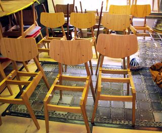 A workshop with multiple seatless wooden chairs on display