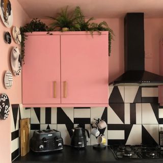 kitchen with pink wall cabinet and graphic monochrome tiles