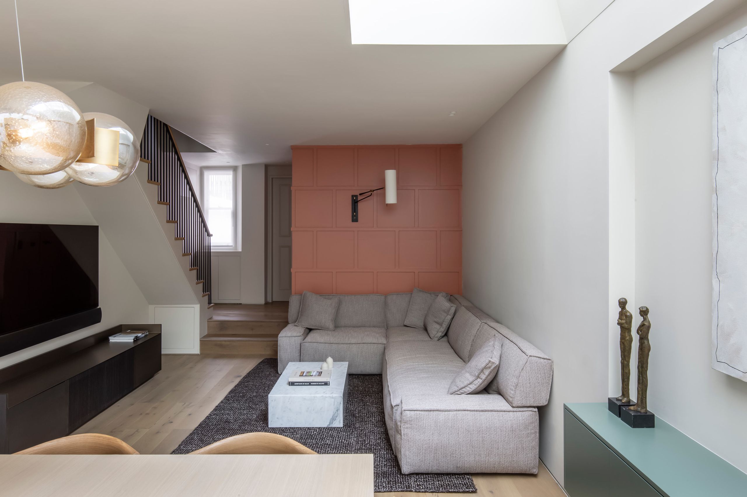 Open plan living room with grey corner sofa and orange panelling feature wall