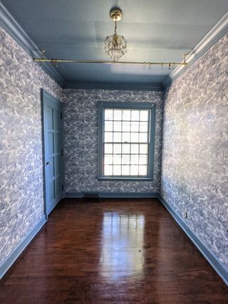 completed freshly stained wooden floor in a small bedroom with blue floral wallpaper