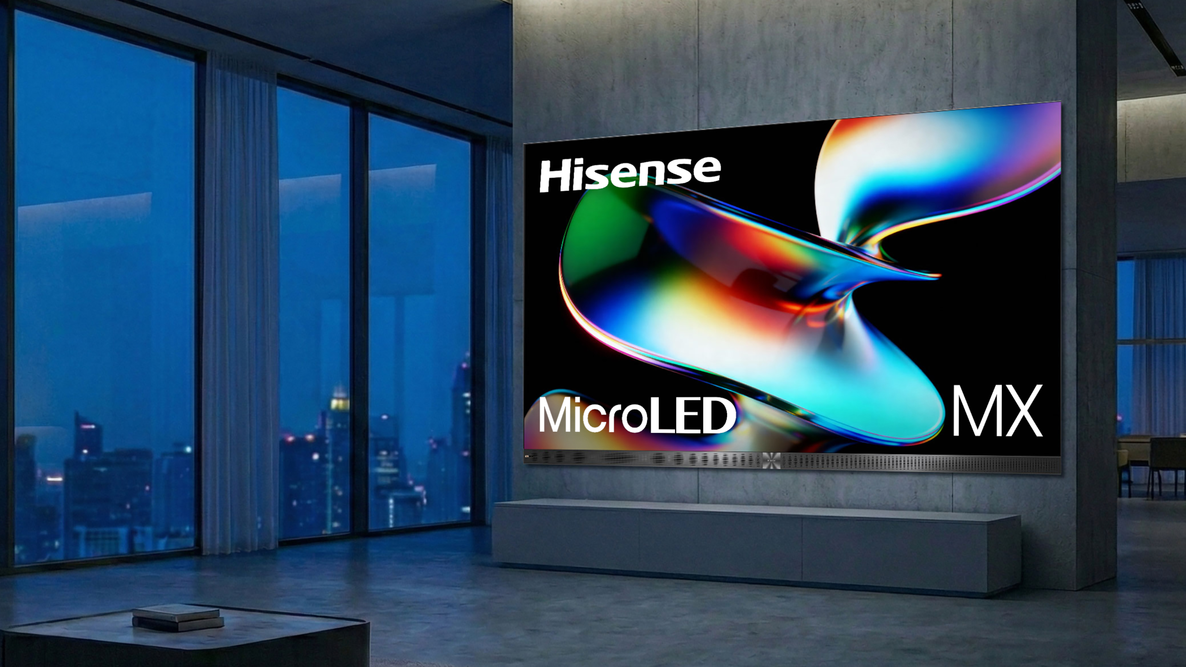 The Hisense 163MX displaying colorful, abstract imagery in a dark, modern condominium with a city skyline at night outside a series of windows in the background.