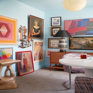 Light blue room filled with colorful large paintings on two walls