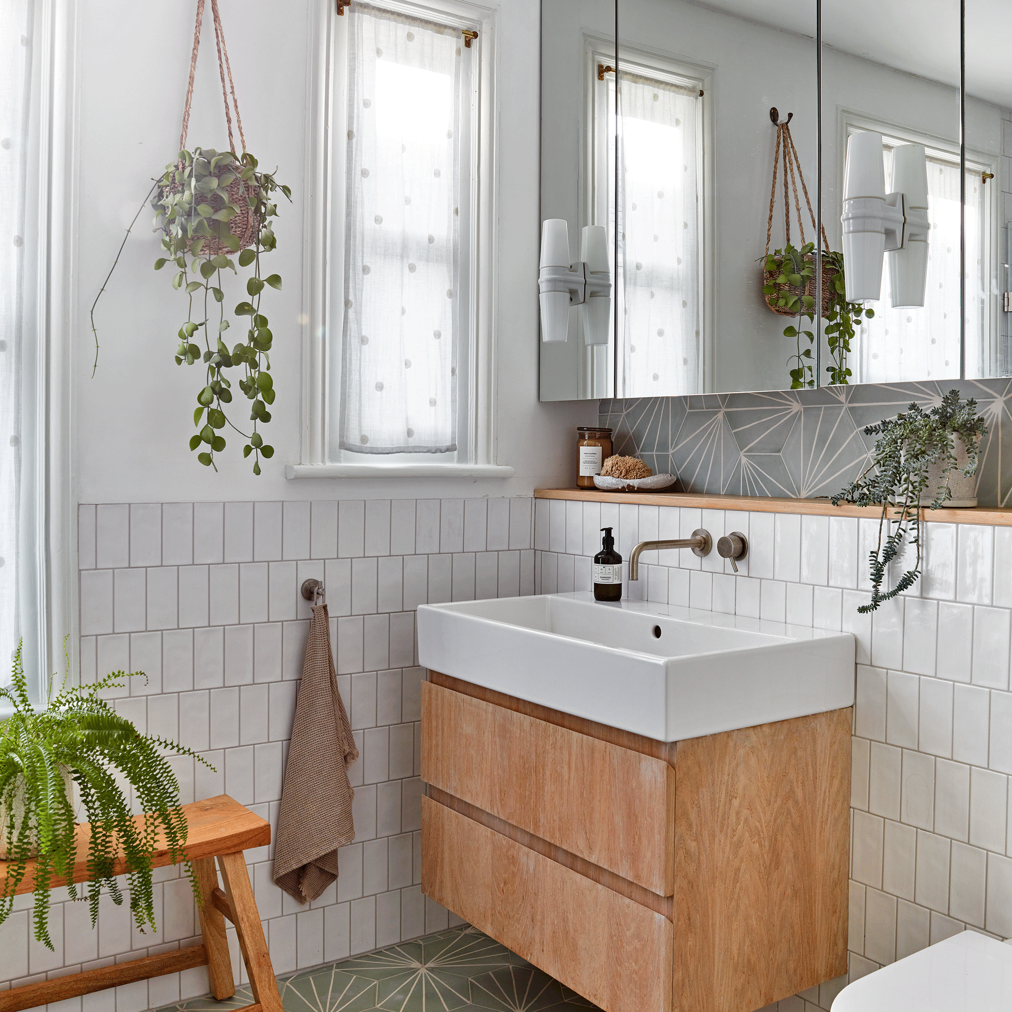 a neutral bathroom with white tiles walls and wooden furniture, alongside several houseplants