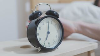 A black alarm clock showing 7am