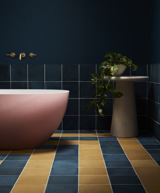 Navy and yellow bathroom with freestanding pink tub