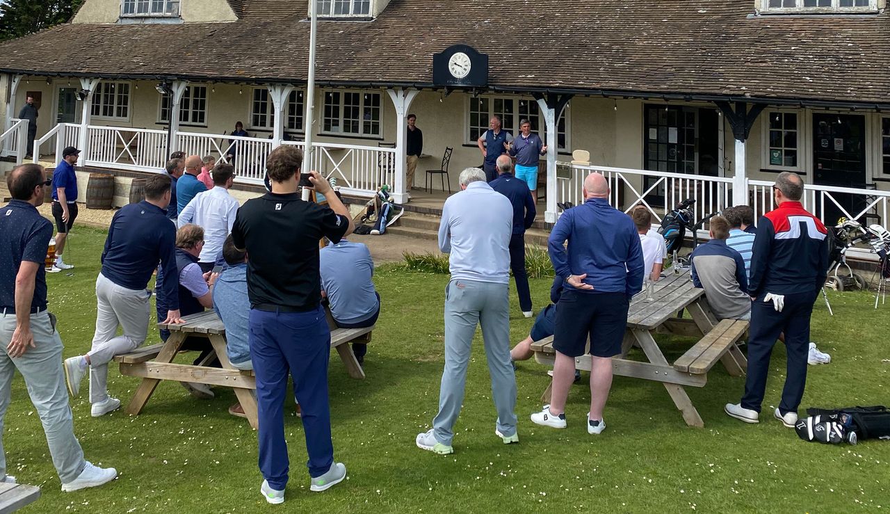 A group surround a man talking at the clubhouse