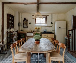 Cozy cottage kitchen with a large wood dining table, a yellow aga, a white smeg fridge, and unfitted kitchen cabinets