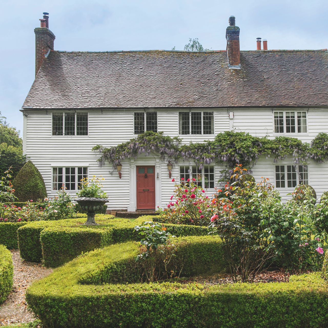 Exterior of white clapboard cottage with box hedges in front garden
