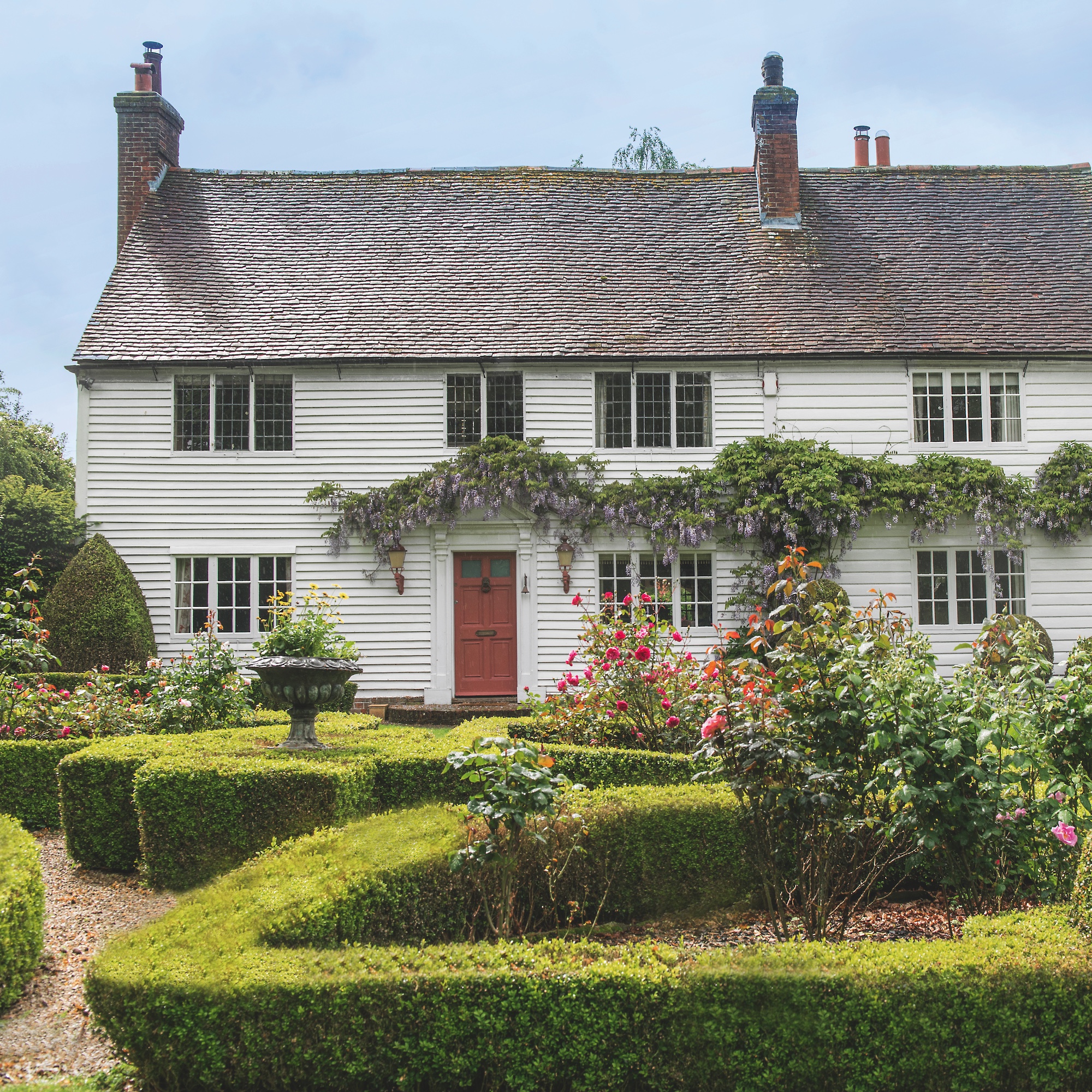 Exterior of white clapboard cottage with box hedges in front garden