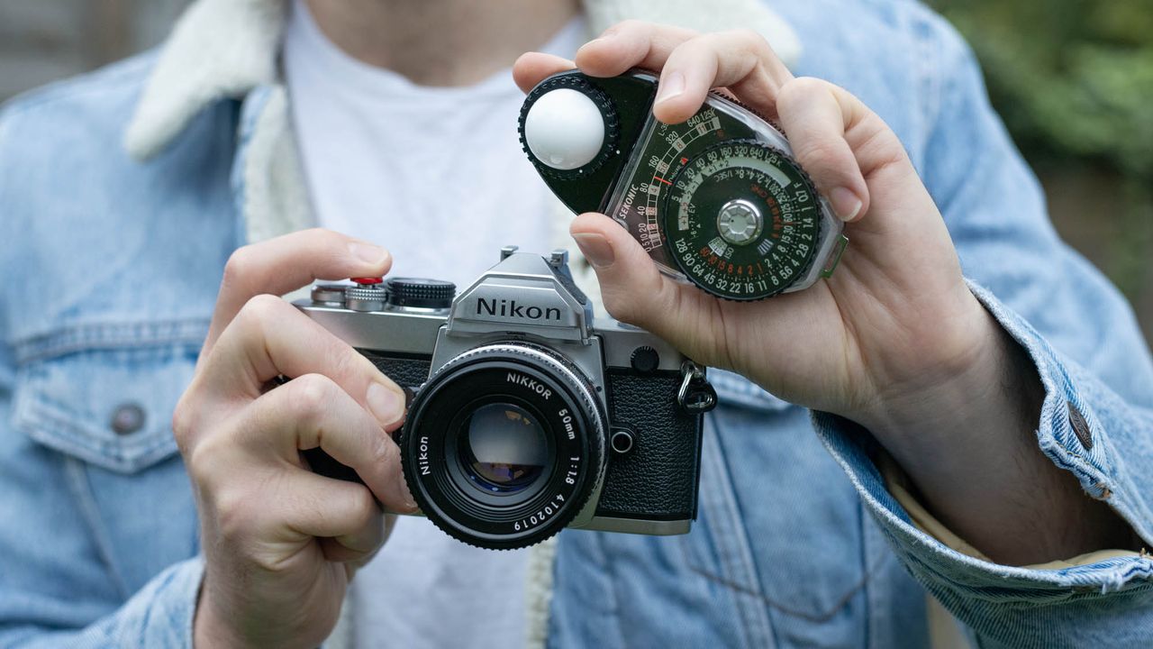 Sekonic Studio Deluxe III L-398A being held next to Nikon FM