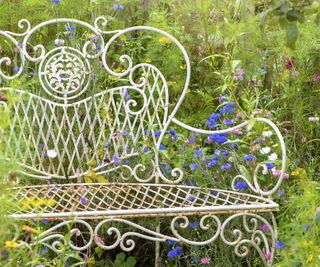 Metal garden furniture with wildflowers behind