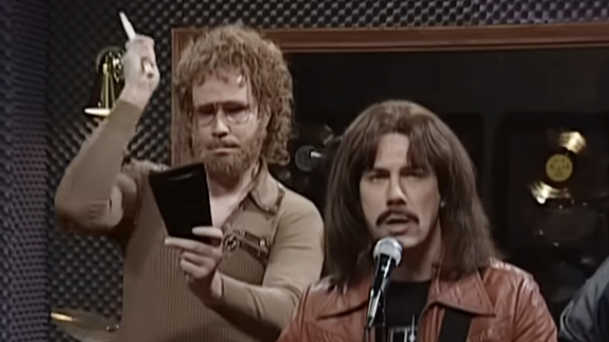 Will Ferrell sporting a wig, beard and a far too tight brown long sleeve shirt, Chris Parnell dressed in brown leather jacket and long brown hair and fake mustache in the legendary 'Cowbell' sketch.
