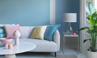 Blue living room decorated in pastel colours with a sofa and lamp